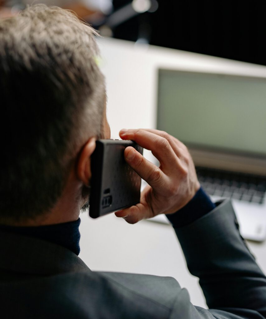 pexels-photo-7793914-7793914 Businessman making a phone call while working on a laptop at the office.